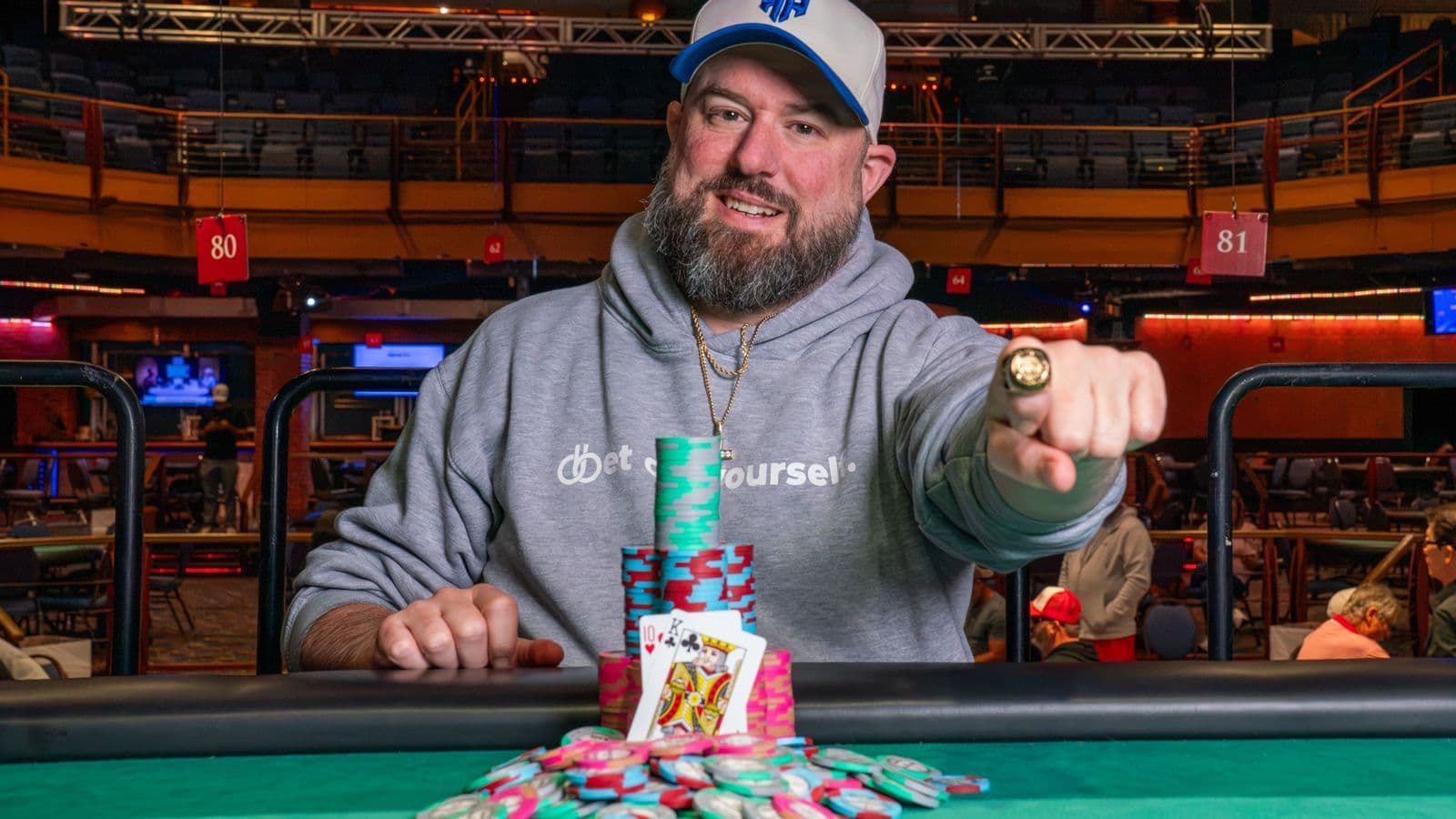 Matt Higgins sosteniendo un anillo WSOPC tras ganar el Main Event en Tunica, junto a cartas de póker y fichas en la mesa