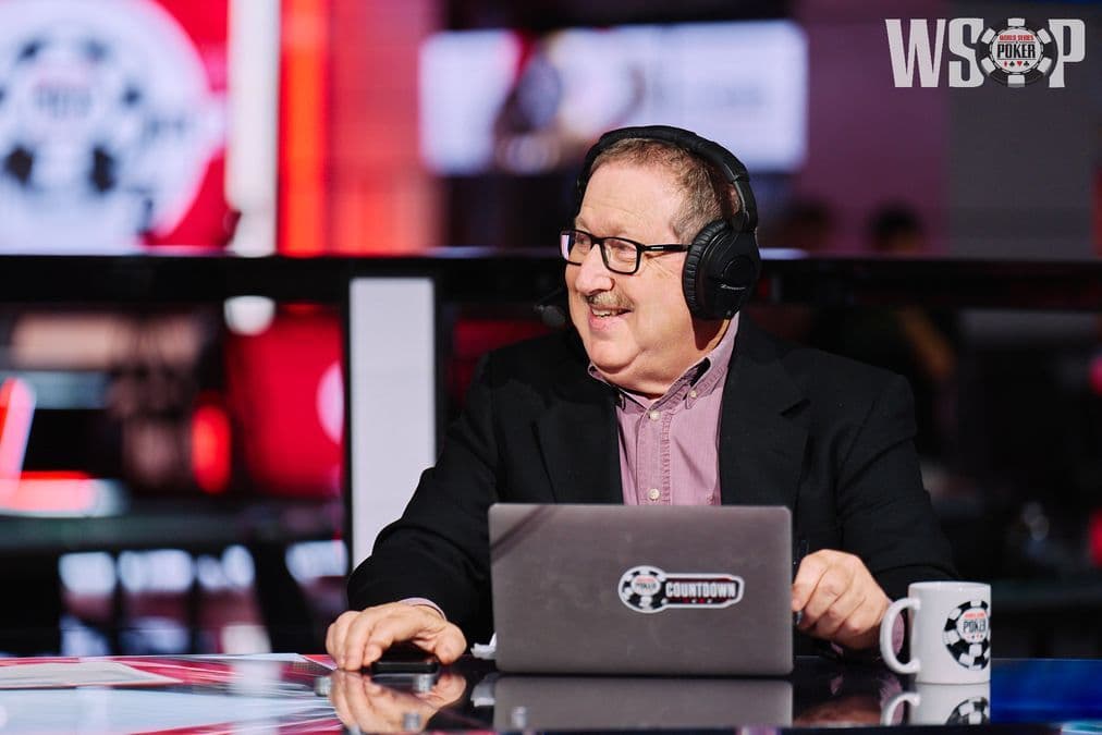 Norman Chad y Lon McEachern en el estudio de transmisión de ESPN del WSOP con el trofeo del Evento Principal 2026 a la vista.
