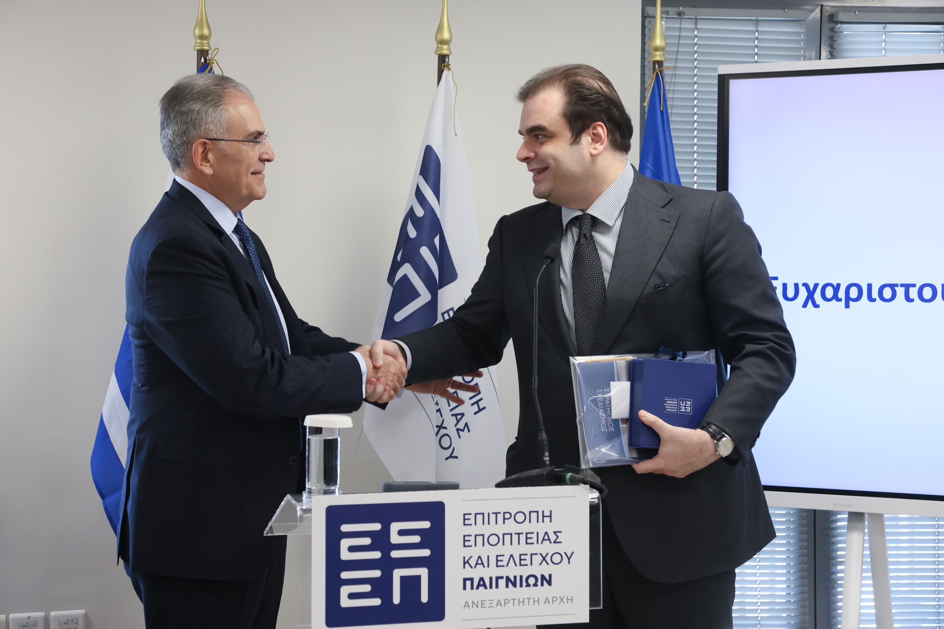 Hellenic Gaming Commission presentation slide and Minister Kyriakos Pierrakakis viewing an AI platform demo in Athens