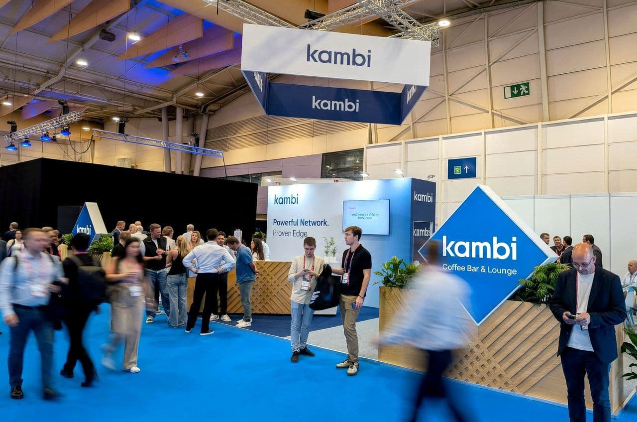 Logotipos de Kambi Group y QuinnBet con interfaz de sportsbook y datos de trading sobre fondo oscuro